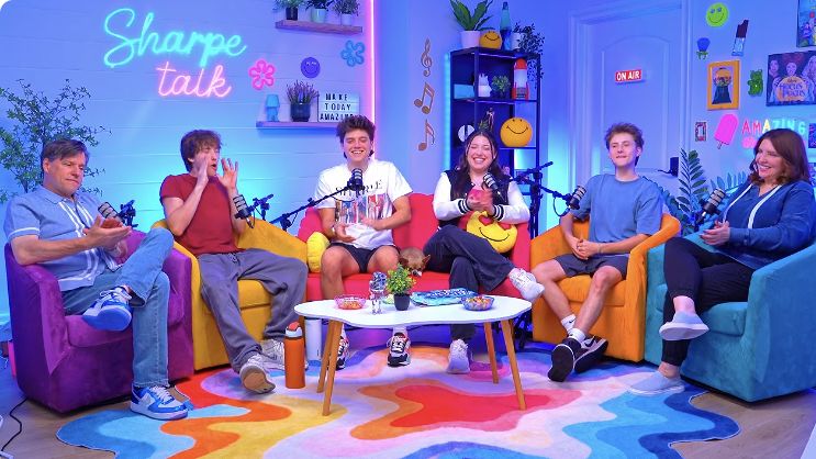 The Sharpe Family talking and laughing at microphones in the colorful Sharpe Talk studio
